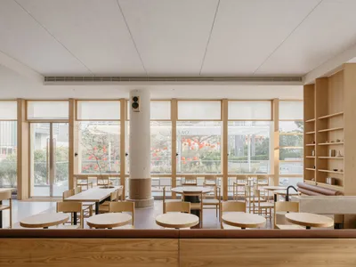 A modern restaurant interior with wooden tables, chairs, and shelves.