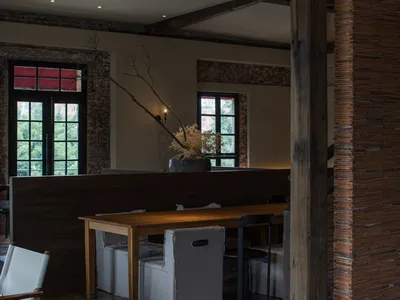 A rustic, industrial-style restaurant interior with exposed wooden beams, brick walls, and a cozy seating area.