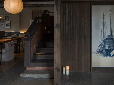 An industrial-style restaurant interior with wooden materials and warm lighting.