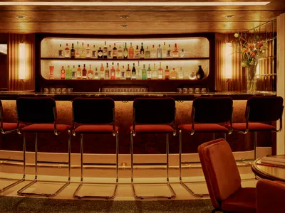 A modern bar with a marble countertop and stools.