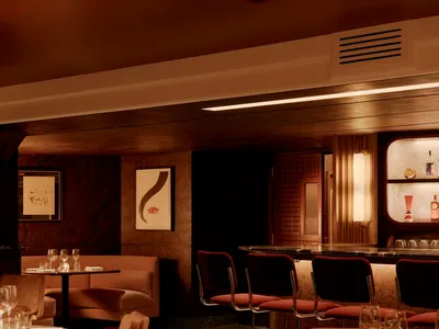 Contemporary restaurant bar with upholstered seating, tables, and barstools, featuring a warm, inviting ambiance created by f