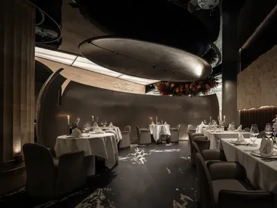Modern restaurant interior with metallic ceiling, wood walls, and fabric seating.