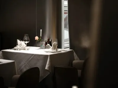 Modern restaurant interior with white cloth table setting and single rose centerpiece.