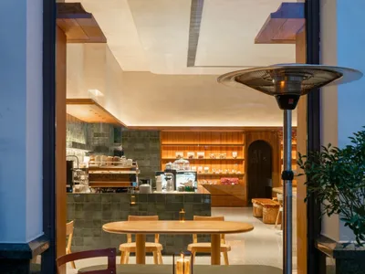 A cafe interior featuring wooden tables and chairs with a concrete floor.