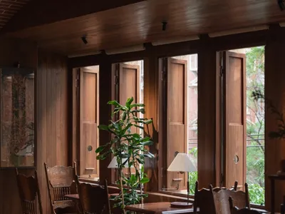 Industrial-style restaurant interior with wooden tables, chairs, and potted plants.
