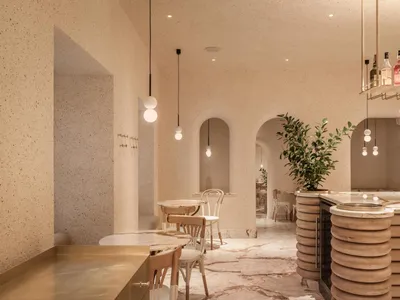 Interior view of a modern restaurant with concrete walls, marble countertops, and wooden furnishings.