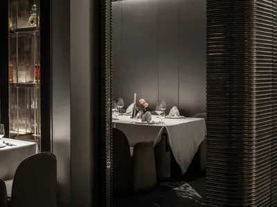 Modern restaurant dining room with metallic elements and white tablecloth.