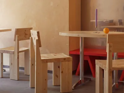 簡約風格的餐廳用餐區，搭配木質家具，並以紅色長椅增添色彩亮點。