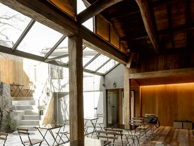 A modern industrial restaurant interior with wooden furniture and a stone staircase.