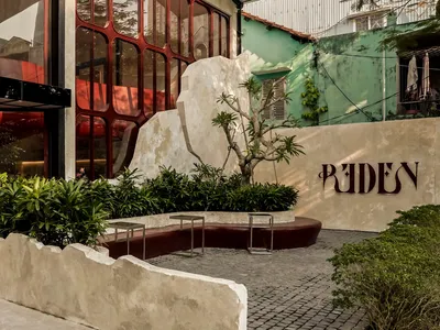 Modern restaurant exterior with concrete materials and greenery.