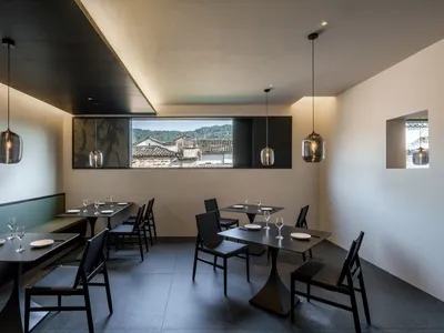 Modern restaurant interior with metallic pendant lights and concrete floor.