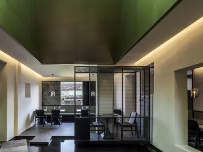現代餐廳室內空間，牆面採用金屬網設計，搭配深綠色天花板。