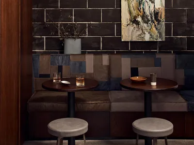 Industrial-themed cafe with dark walls, leather benches, and round tables.