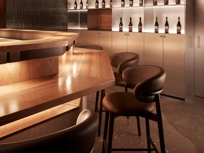 Contemporary bar interior with wooden counter and stools, showcasing modern design elements and materials.