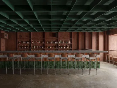 Industrial-style restaurant interior with wooden accents, concrete countertops, and metal stools.