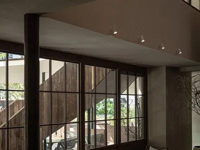 An indoor space with industrial design featuring wooden furniture and walls, glass windows, and comfortable seating options.
