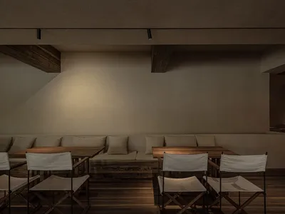 Industrial-style restaurant interior featuring wooden tables and cushioned seating.