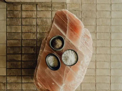 A minimalist kitchen with a large, raw stone slab featuring three small bowls containing different types of spices.