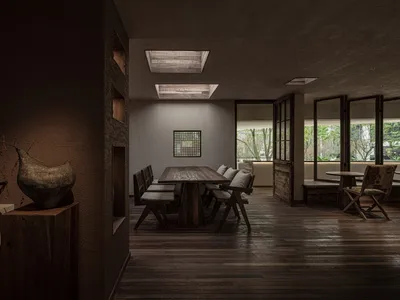 A modern restaurant dining room features a wooden table with cushions and chairs.