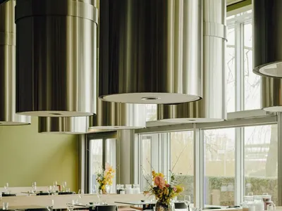 Modern restaurant interior with metal and wooden features, including booths and tables arranged in a spacious, open layout.