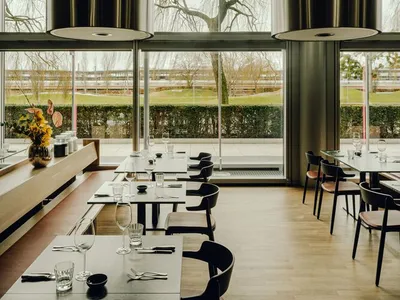 A modern restaurant interior with metallic walls and wooden flooring.