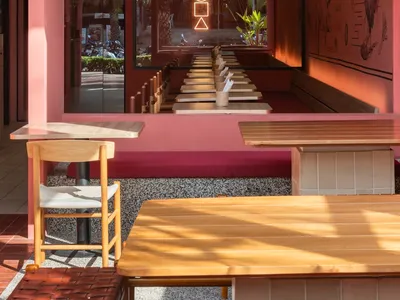 A cafe bar with wooden furniture, indoor lighting, and a vibrant exterior view.