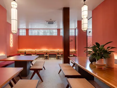 Cafe interior with wooden furniture, red walls, and modern lighting.