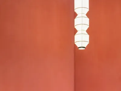 極簡餐廳空間，擺放紅色壓克力餐桌，搭配木質長椅與混凝土底座。