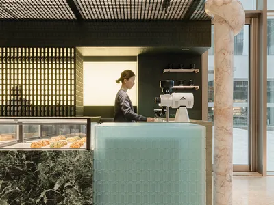 A minimalist coffee shop interior featuring a glass counter with a marble column.