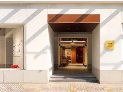 Modern restaurant cafe exterior featuring white concrete, stone, and timber materials.