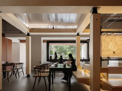 Interior of a modern restaurant featuring wood, concrete, and glass materials.