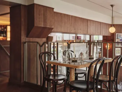 Modern, minimalist restaurant interior with wooden tables, metal chairs, and a warm, inviting atmosphere
