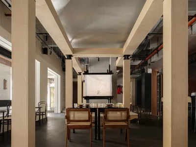 A sleek, minimalist restaurant interior with metallic columns and an exposed ceiling infrastructure.