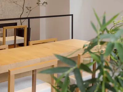現代餐廳室內，擺設木質桌椅，大型窗戶展示戶外綠意。