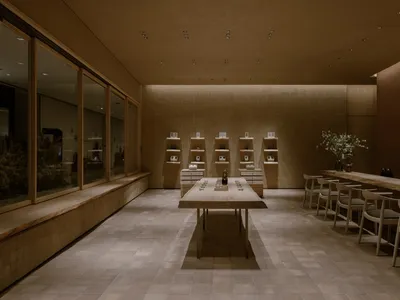 A minimalist restaurant interior featuring wooden furniture and shelves.
