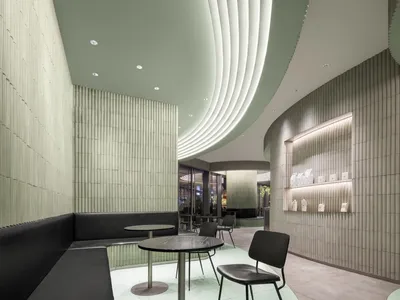Contemporary restaurant interior with textured concrete walls and ceiling, modern furniture, and sophisticated lighting.