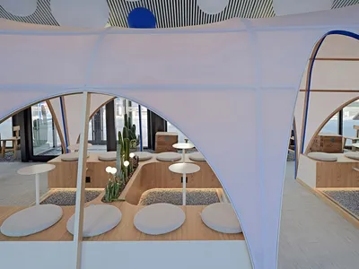 A modern industrial restaurant lobby with cushioned seating, a cactus centerpiece, and high ceiling.