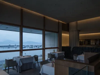 Modern restaurant interior with glass windows overlooking the ocean.