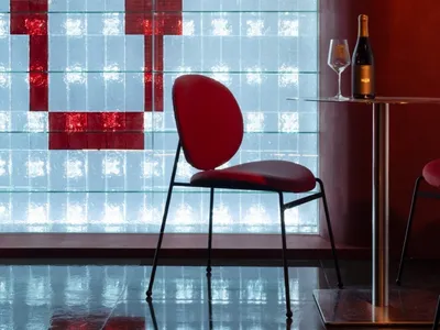 A modern restaurant interior featuring a large glass window system with a red geometric design.