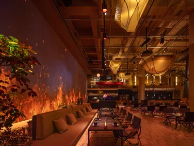 Industrial-themed restaurant interior with concrete walls, exposed steel, and glass elements.