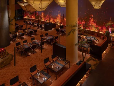 Modern dining hall with wooden floors, metal furniture, and glass elements.