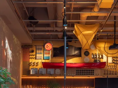 A modern industrial restaurant interior with exposed brick walls, wooden tables, and hanging lights.