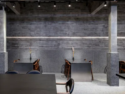 Modern restaurant interior with industrial design elements, featuring concrete, granite, and metal materials.