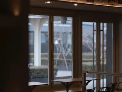 Indoor restaurant interior with wooden tables and chairs, industrial design elements, and natural light.
