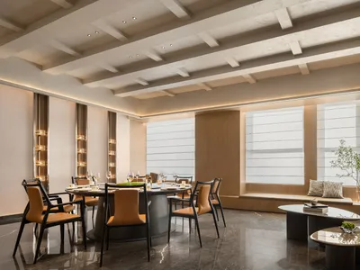 Modern restaurant interior featuring marble floors, black and brown leather dining chairs, and a table with wine glasses and
