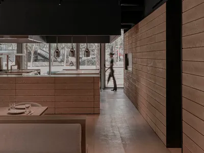 Industrial-style restaurant interior featuring wooden walls and concrete surfaces.