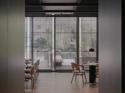 Modern restaurant interior with wooden seating, metal railings, and glass partitions