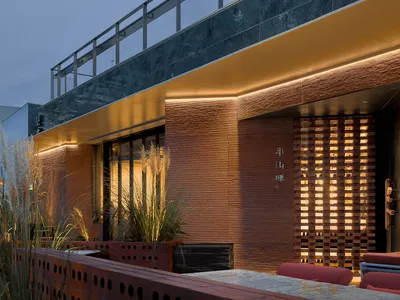 Modern restaurant exterior with brick facade and glass doors during a night setting.