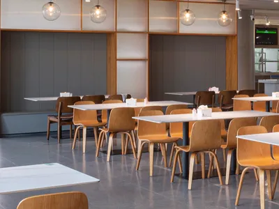 A spacious, industrial-style restaurant interior featuring timber furniture and white tables and chairs.