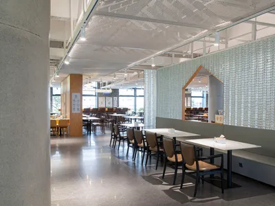 Modern, minimalist restaurant interior with concrete elements, clean lines, and a mix of seating options.